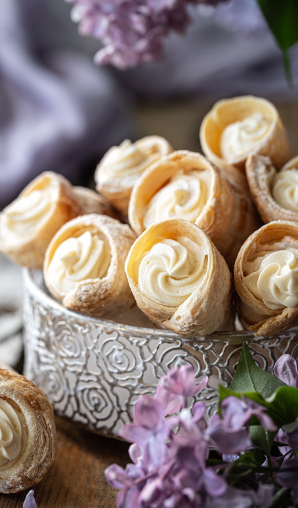Трубочки с кремом на столе с цветами сирени