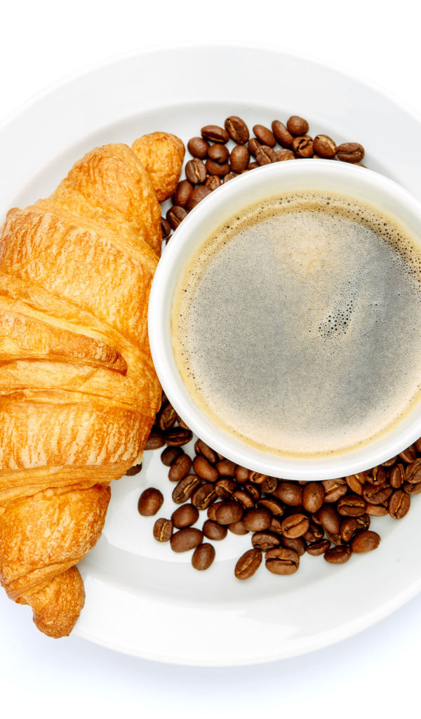 Чашка кофе на белой тарелке с круассаном и зернами, вид сверху 