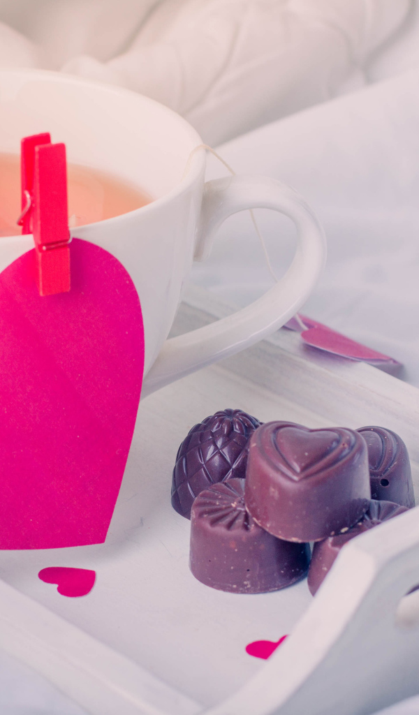 Чашка кофе с красным сердцем и шоколадными конфетами 