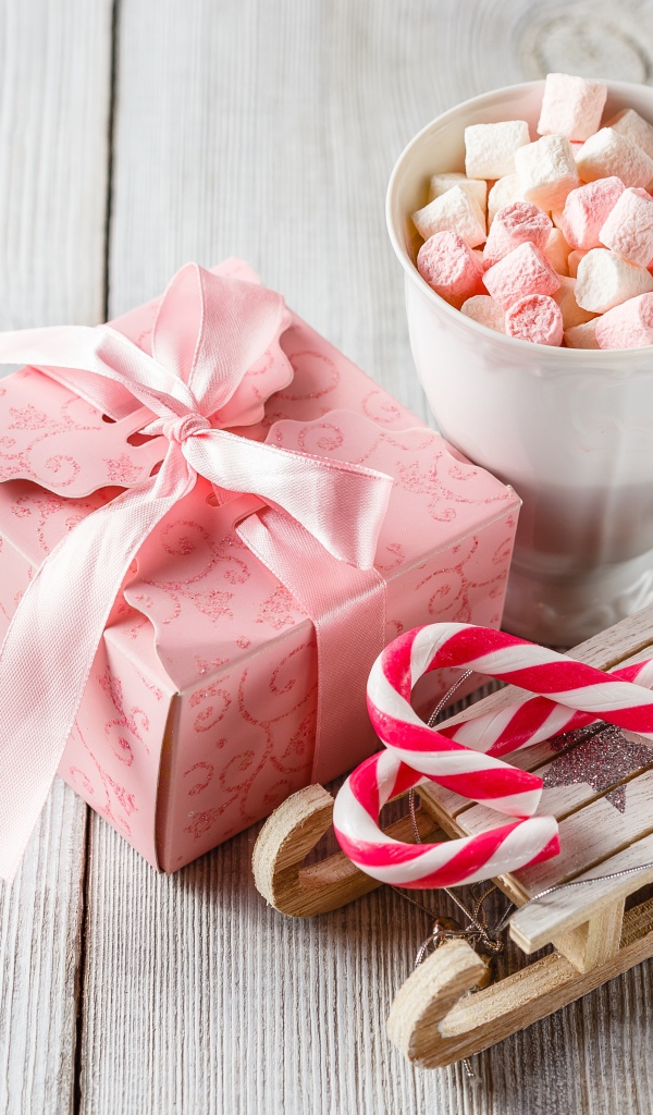 Чашка с маршмеллоу на столе с игрушечными санками и подарком