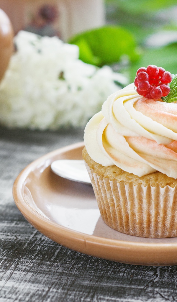 Кекс с кремом и малиной на столе