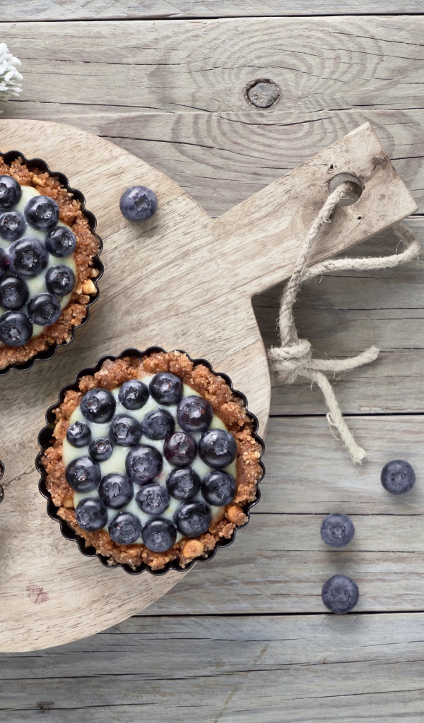 Кексы с кремом и ягодами черники на столе с чайными ложками