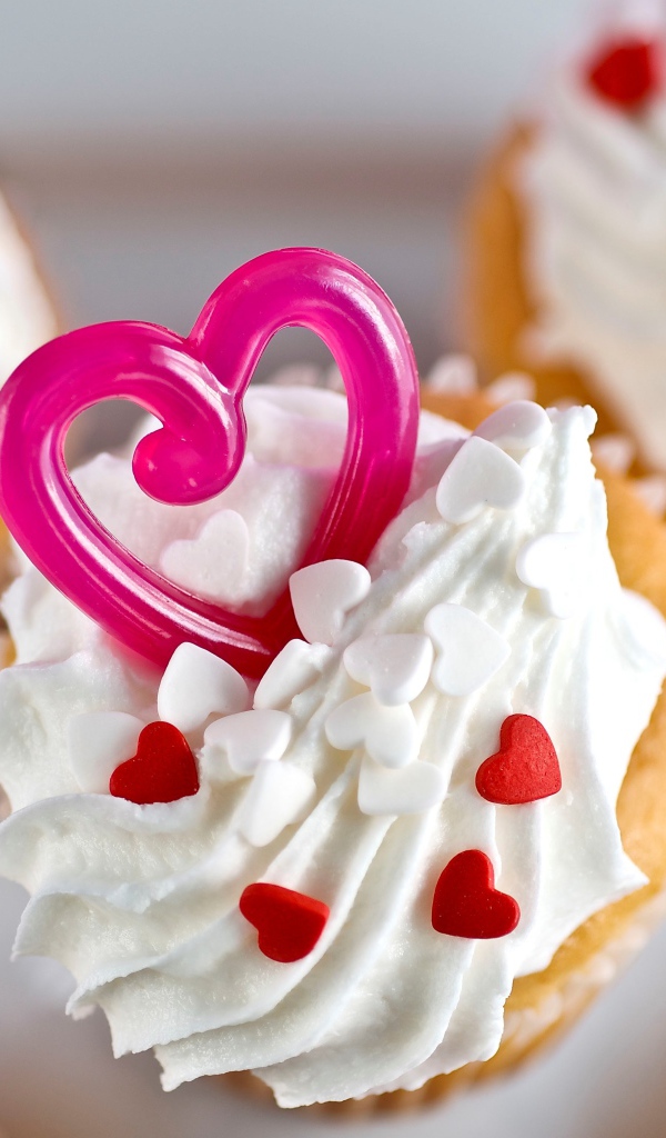 Кексы с кремом и сердечками на столе 