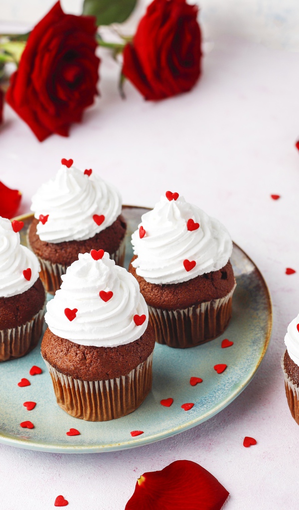 Кексы с кремом на столе с букетом роз 