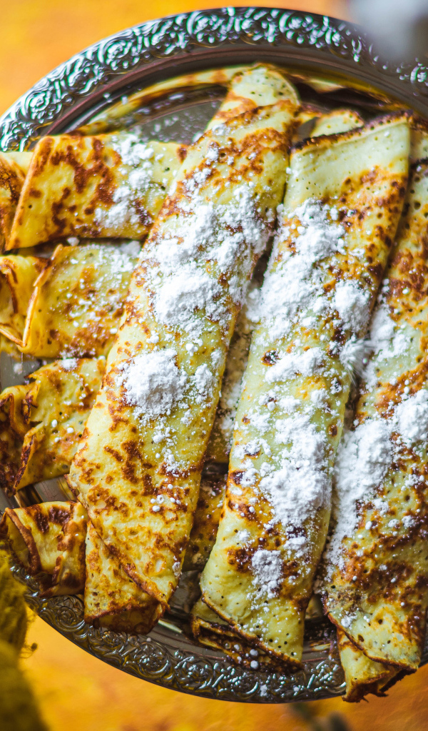 Вкусные тонкие блины с сахарной пудрой на блюде