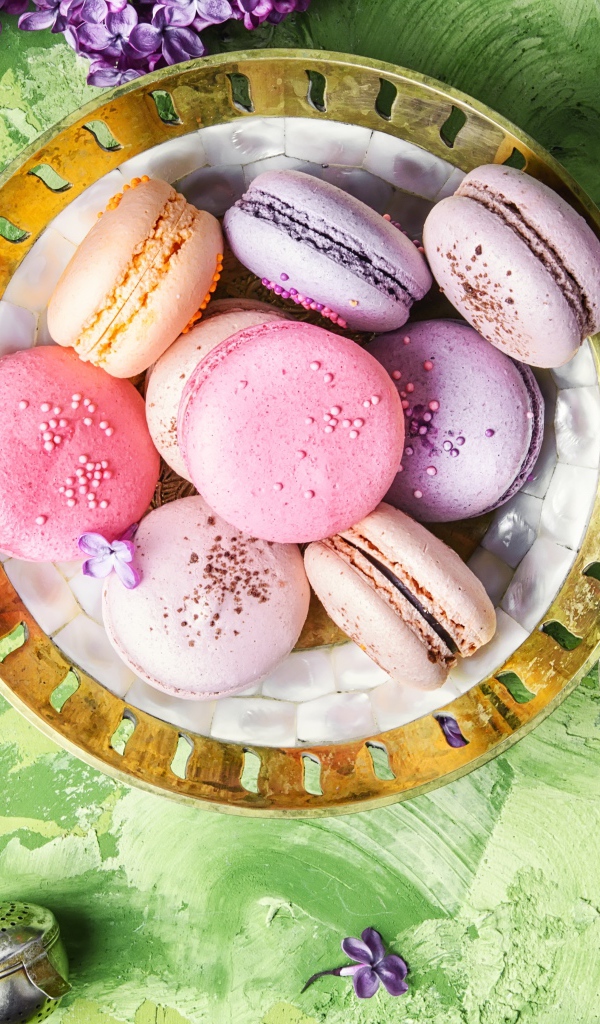 Разный десерт макарон на столе с цветами сирени 