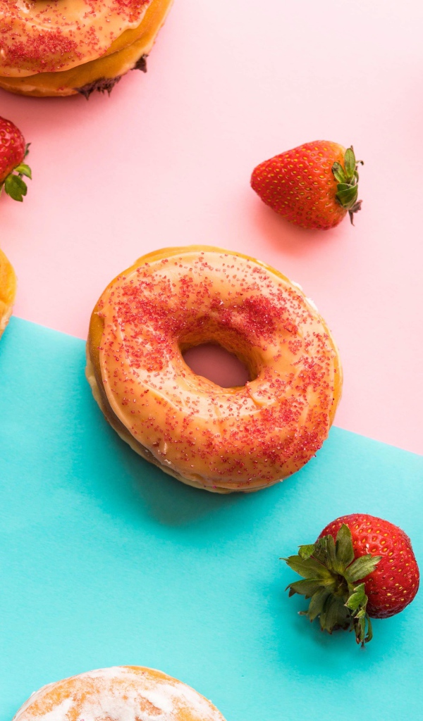 Пончики с глазурью на столе с ягодами клубники