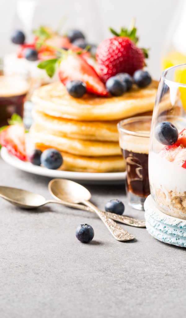 Оладьи на столе с ягодами, мюсли и кофе