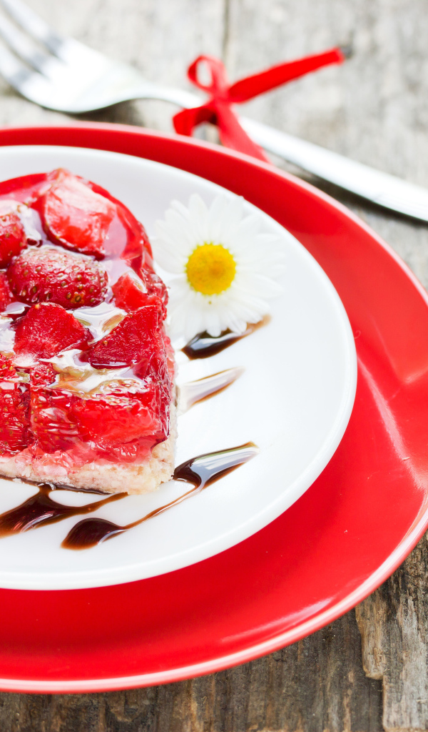 Пирожное с клубникой в форме сердца на тарелке с ромашками