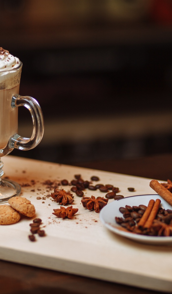 Горячее какао со сливками на столе с печеньем, зернами кофе и пряностями 