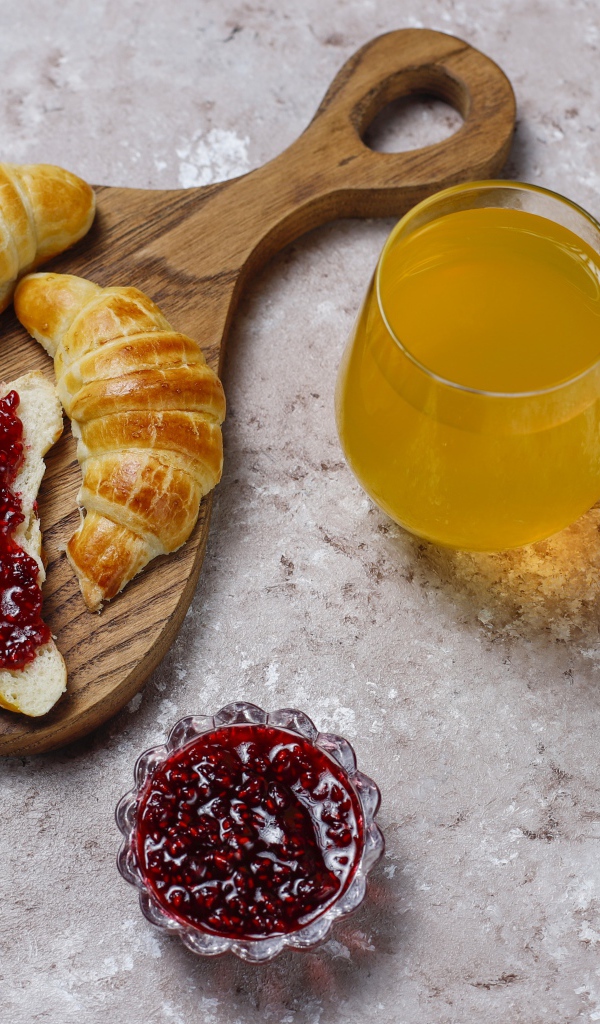 Сок на столе с круассанами и джемом