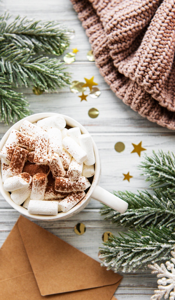 Кружка с маршмеллоу на столе с еловыми ветками и свечой