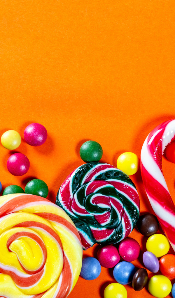 Разноцветные конфеты на оранжевом фоне