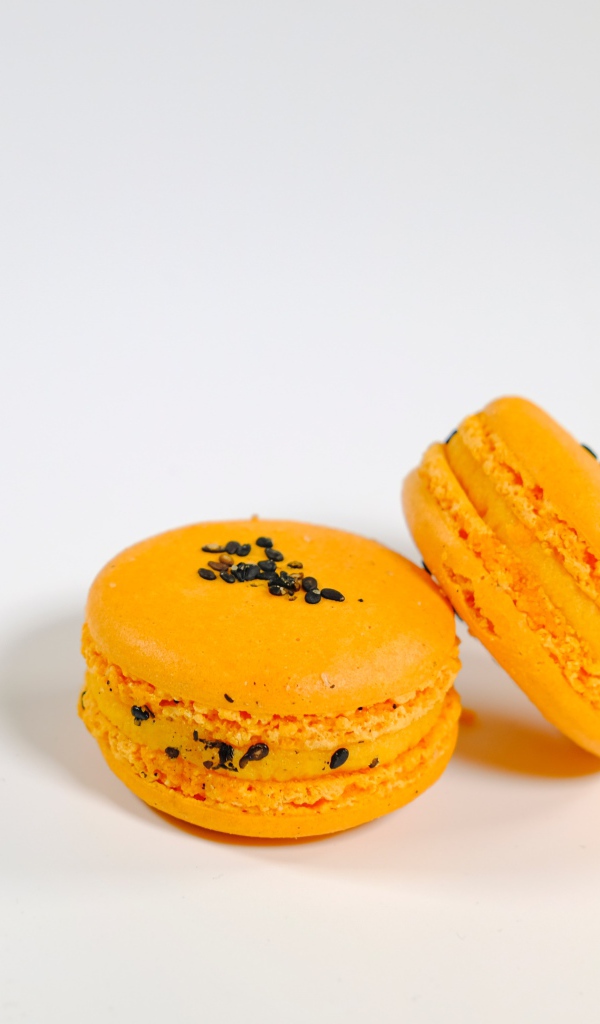 Оранжевый десерт макарон на сером фоне