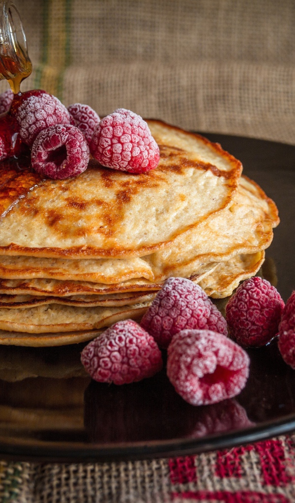 Блины с сиропом на тарелке с малиной