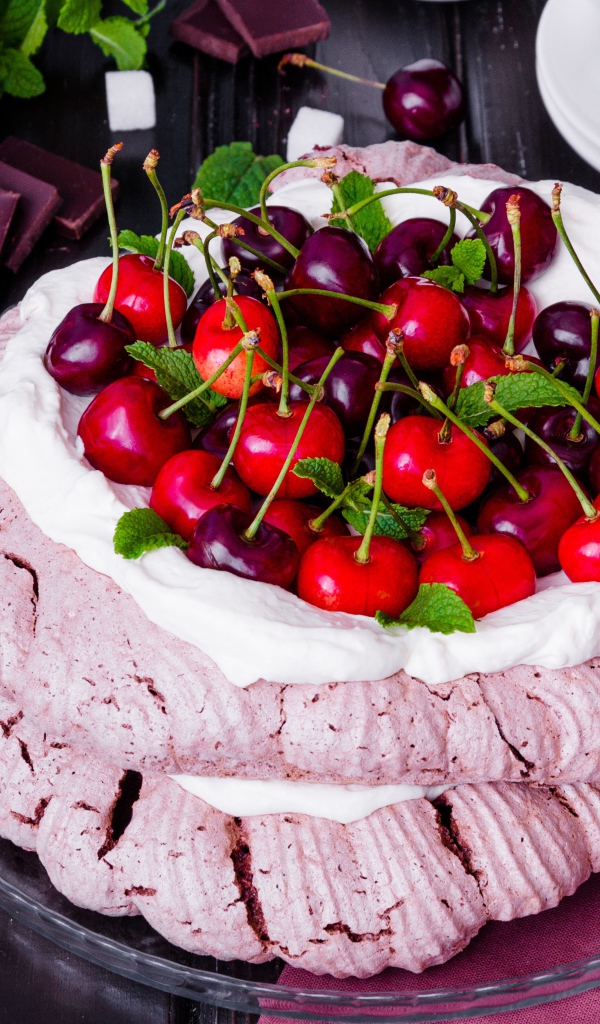 Торт Павлова со сливками и ягодами черешни на столе