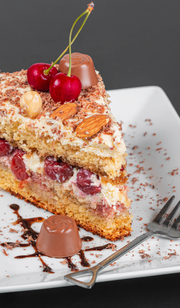 Кусок торта с ягодами вишни и миндальным орехом