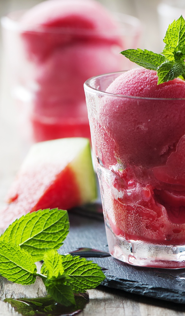 Фруктовое мороженое в стакане на столе с кусочками арбуза и мятой