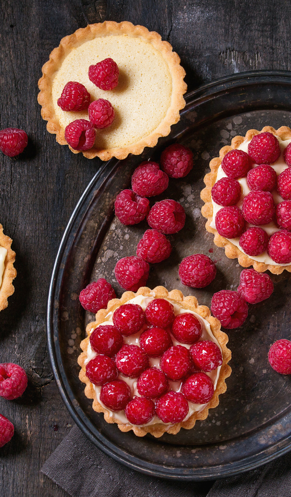 Кексы с кремом на блюде с малиной 