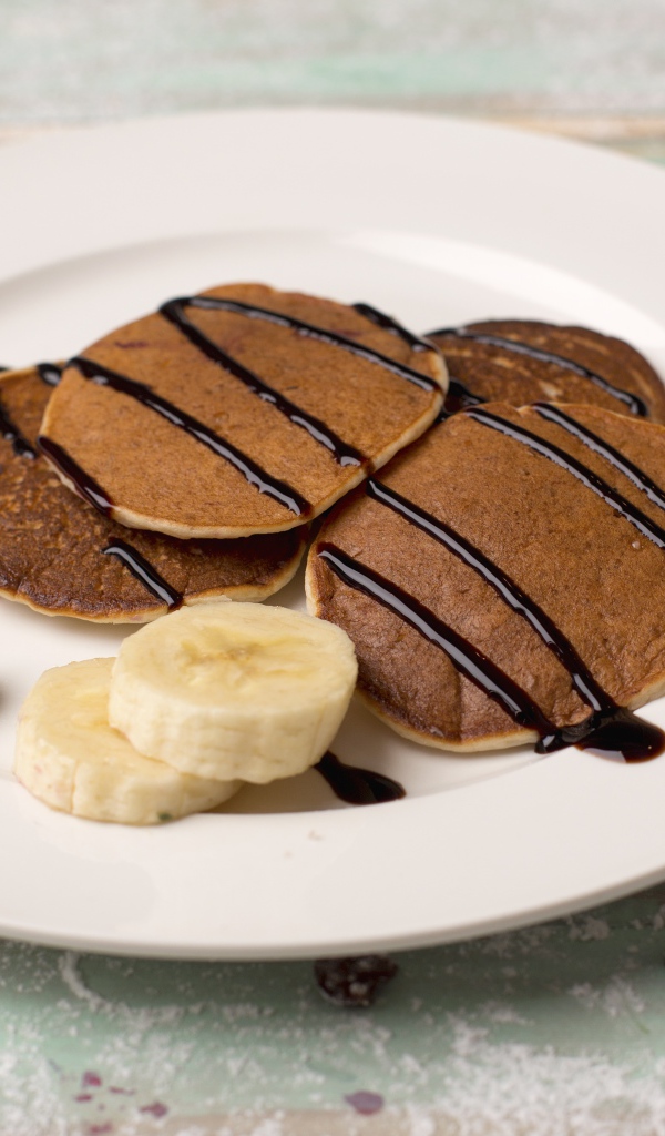 Румяные оладьи с бананом на белой тарелке 