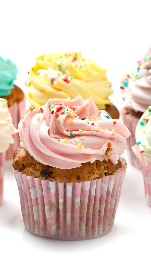 Сладкие кексы с кремом и посыпкой на белом фоне