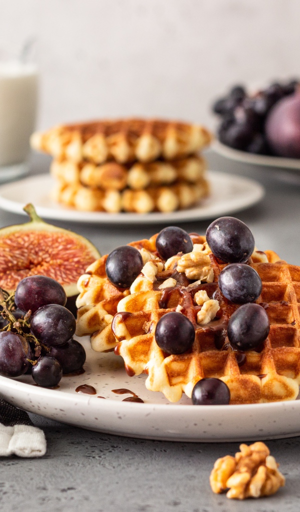 Сладкие вафли на тарелке с инжиром и виноградом