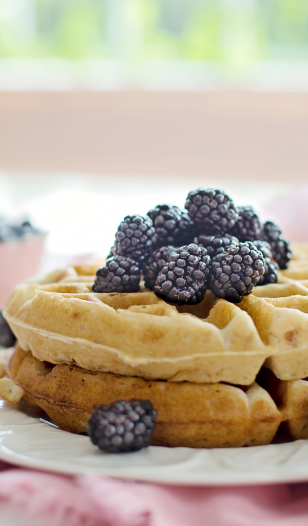 Сладкие вафли на белой тарелке с ягодами ежевики