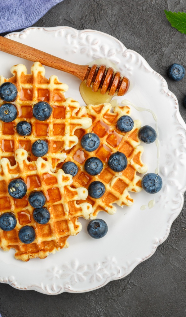 Сладкие вафли с медом на тарелке с ягодами черники