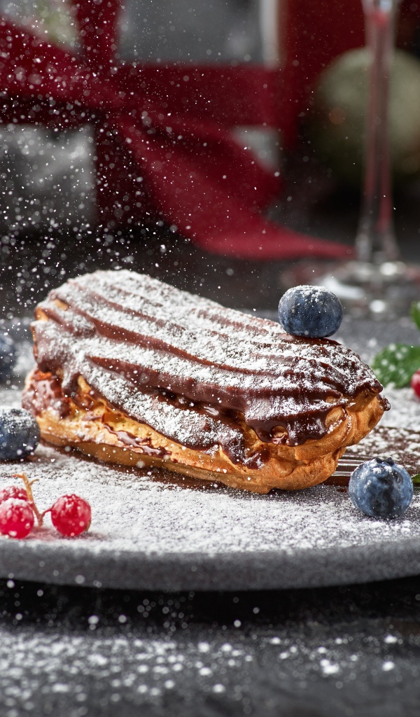 Вкусное пирожное на тарелке с сахарной пудрой и ягодами