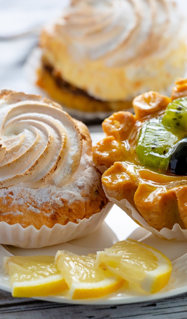 Вкусные аппетитные пирожные на тарелке с лимоном