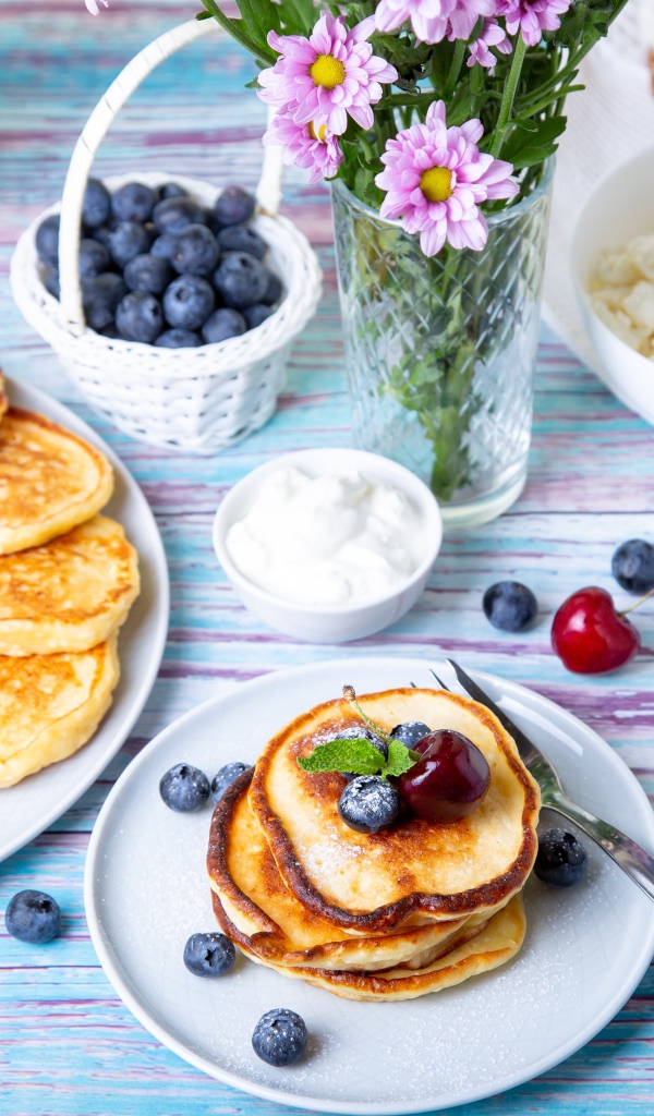 Вкусные оладьи на столе с ягодами черники, творогом и молоком
