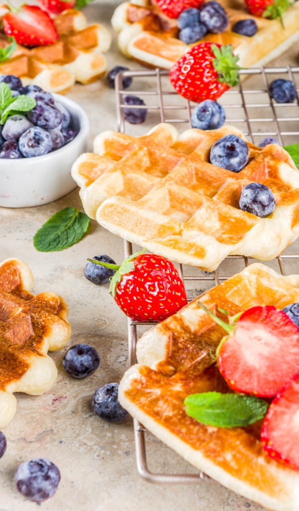 Вкусные сладкие вафли на столе с ягодами черники и клубники