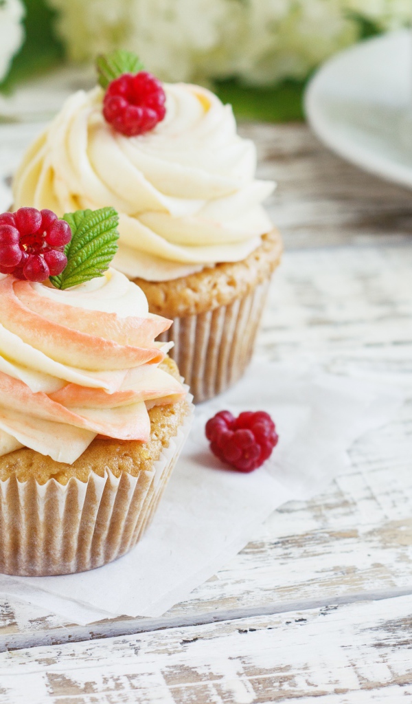 Три кекса с кремом на столе с чашкой кофе