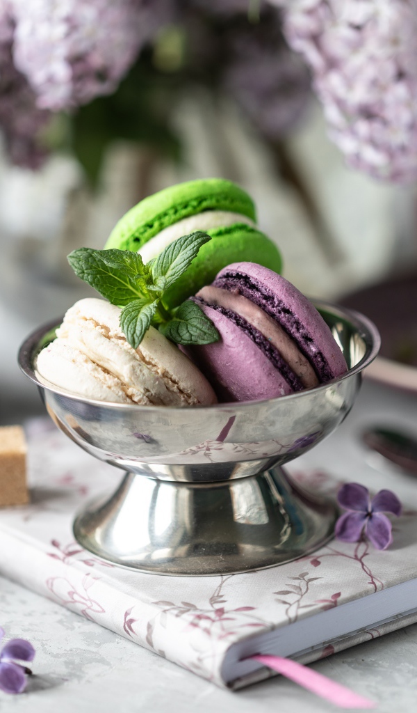 Три печенья макарун на столе с блокнотом