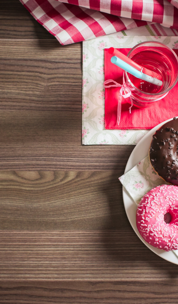 Три сладких пончика с глазурью на столе с лимонадом