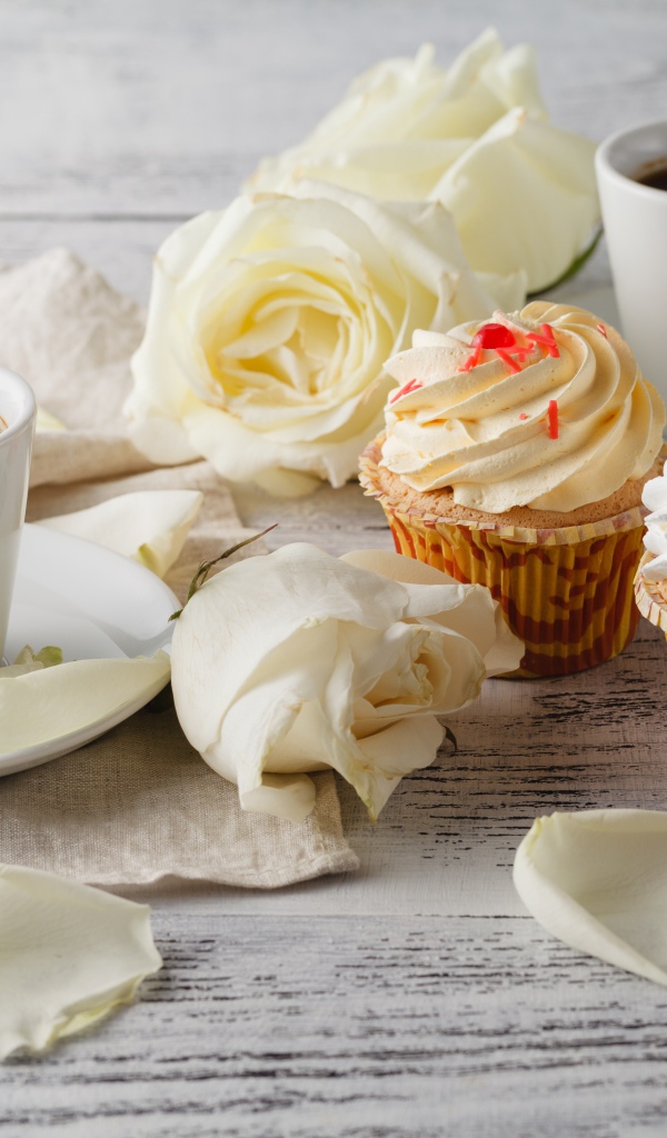 Две чашки кофе на столе с белыми розами и кексами