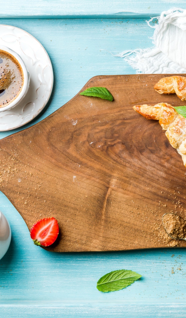 Деревянная доска на столе с круассанами и чашкой кофе