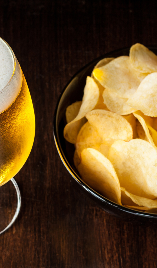 Миска с чипсами на столе с бокалом пива 