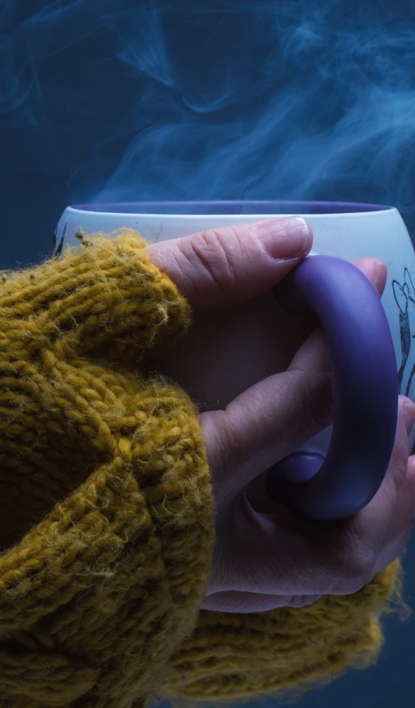 Чашка горячего кофе в руках у девушки на сером фоне