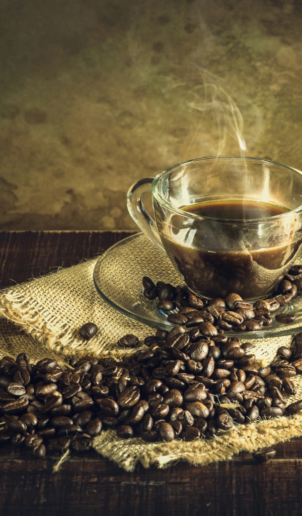 Чашка горячего крепкого кофе на столе с зернами