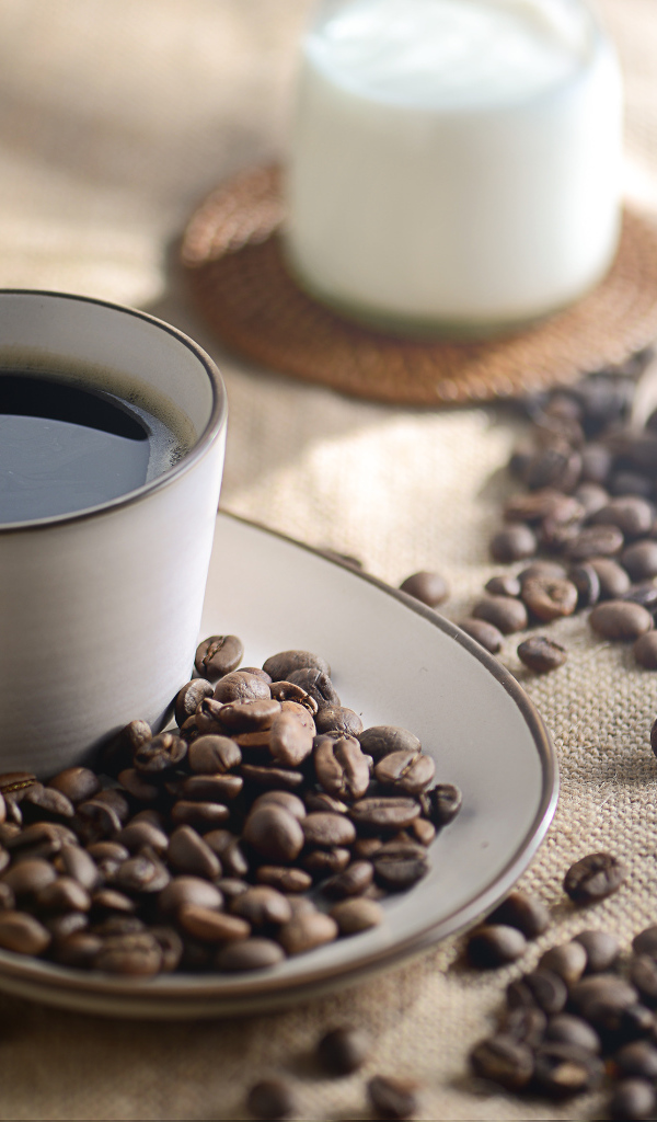 Чашка крепкого кофе на столе с зернами