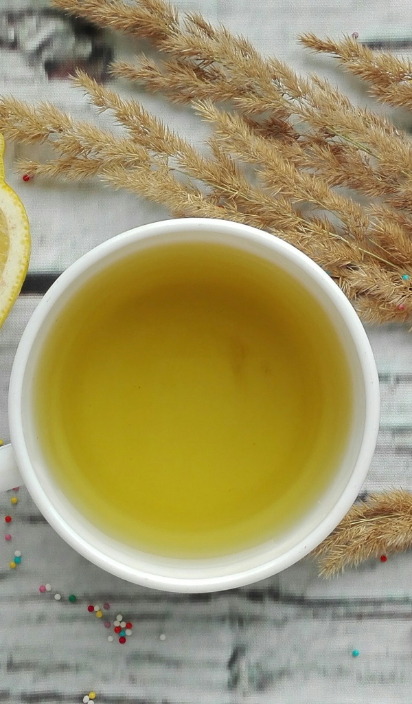 Чашка чая на столе с лимоном и колосьями