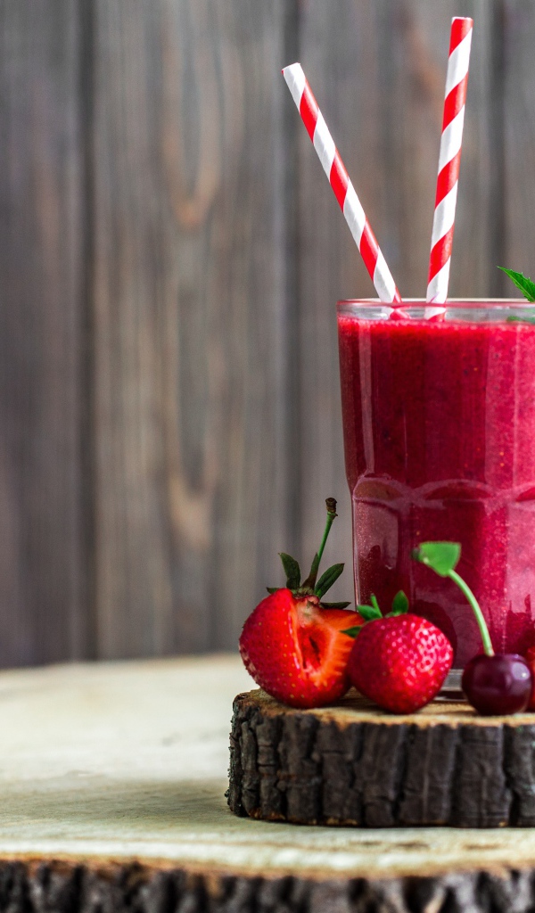 Стакан ягодного смузи на столе с клубникой и вишней