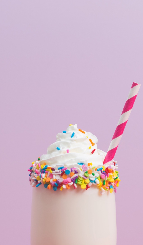 Коктейль  в стакане со взбитыми сливками на розовом фоне