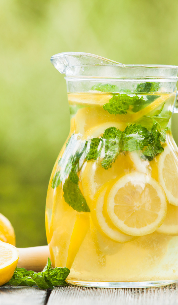 Лимонад в графине на столе с лимонами