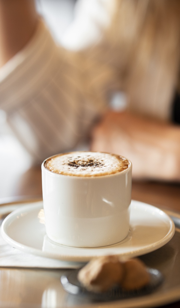 Чашка капучино с корицей на столе в кафе