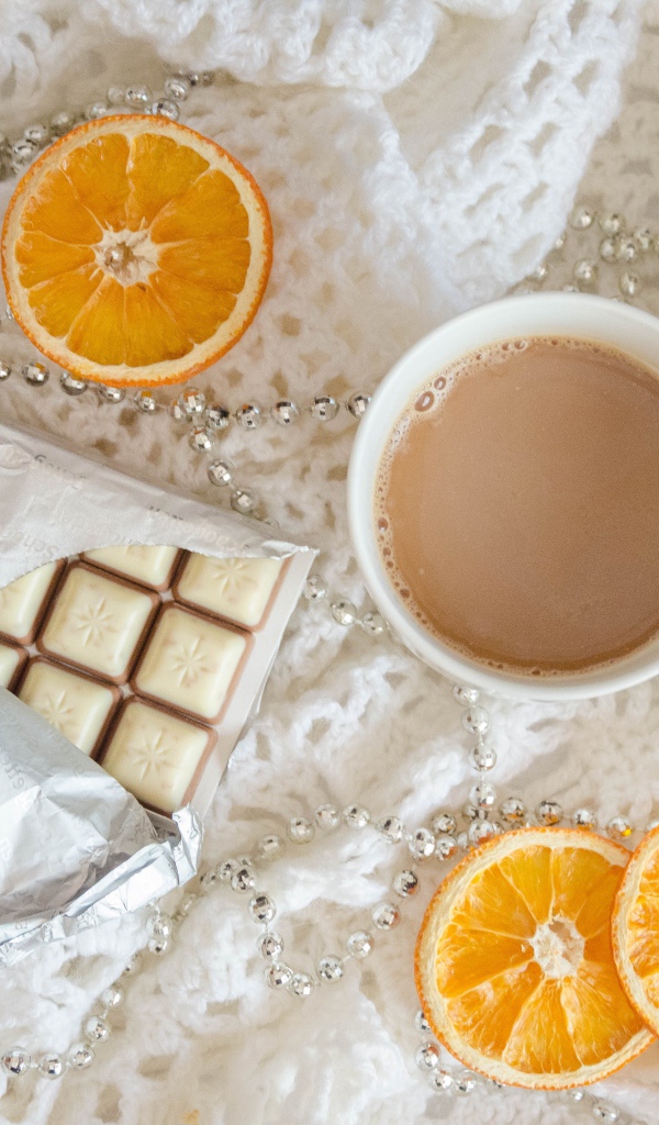Чашка какао, шоколад и апельсин на белом пледе