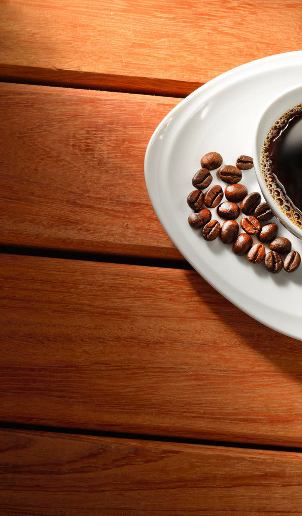 Чашка кофе на тарелке с зернами на деревянном столе