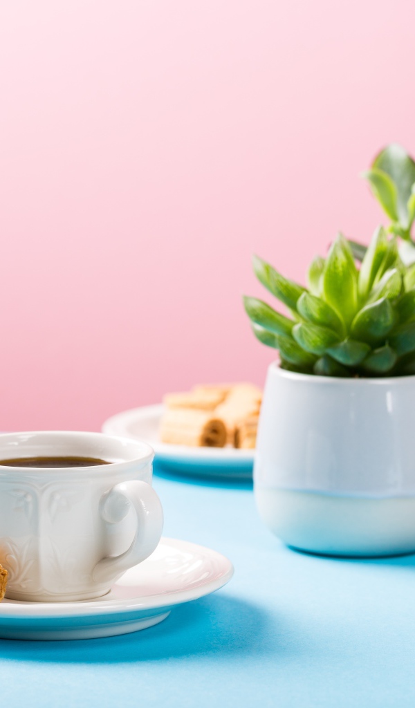 Чашка кофе на блюдце с вафлями на столе с цветами