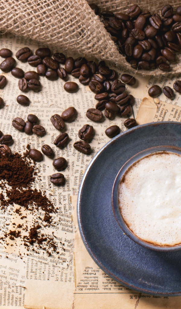 Чашка кофе на столе со старыми газетами и зернами